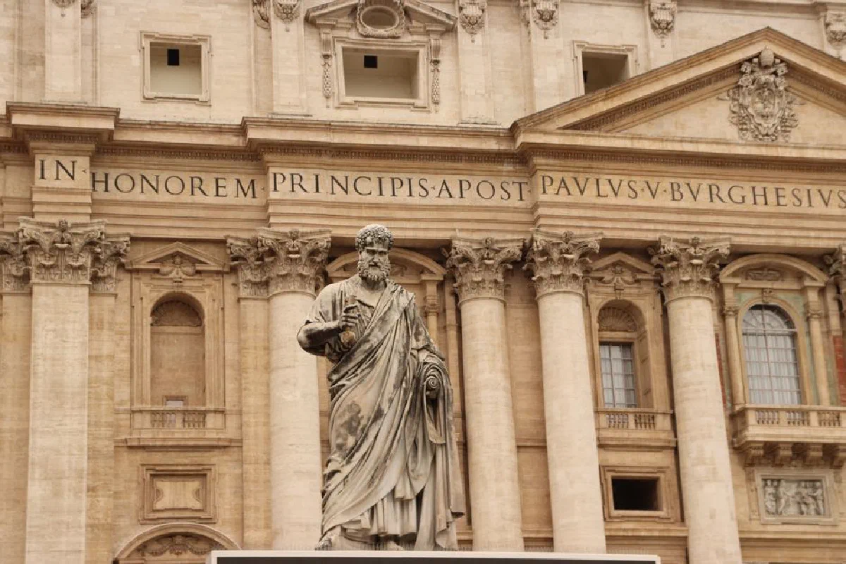 St. Peter statue in front of St. Peter's Basilica facade in Vatican City, showcasing classic architecture.