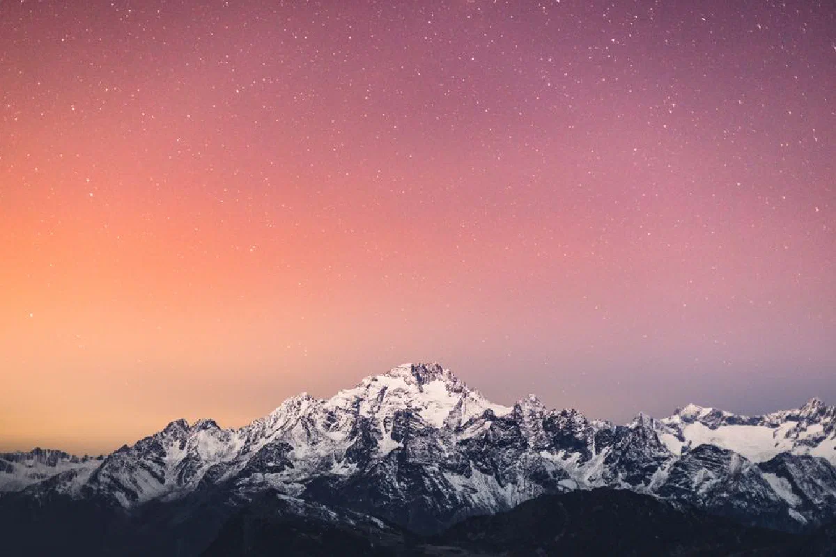 Beautiful snow-covered mountains under a starry sky at twilight in Lanzada, Lombardy.