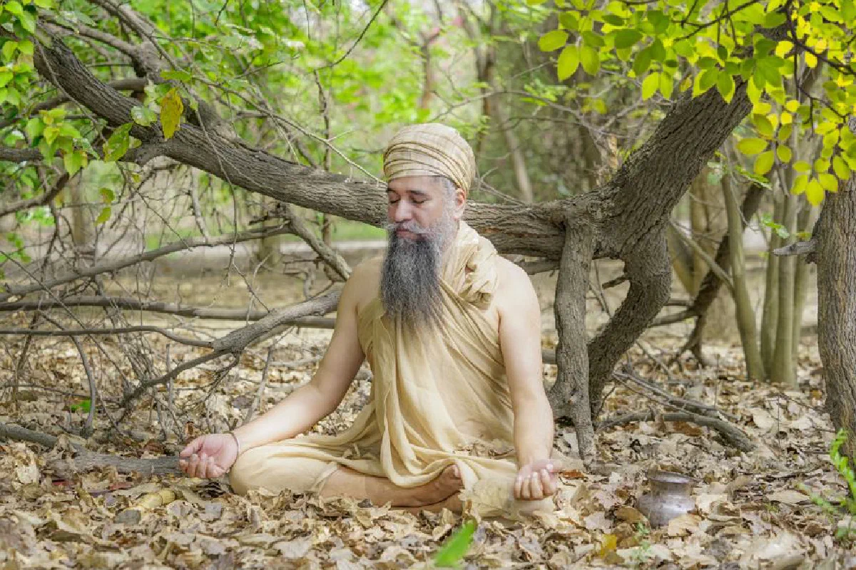 A man meditating in a forest wearing traditional clothing, exuding spirituality and tranquility.