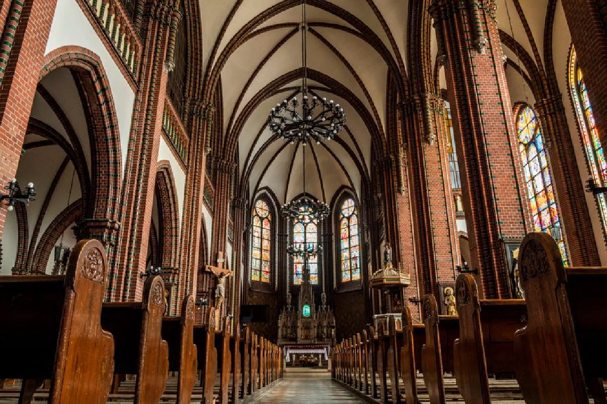Intricate Gothic cathedral interior showcasing stained glass windows and wooden pews.