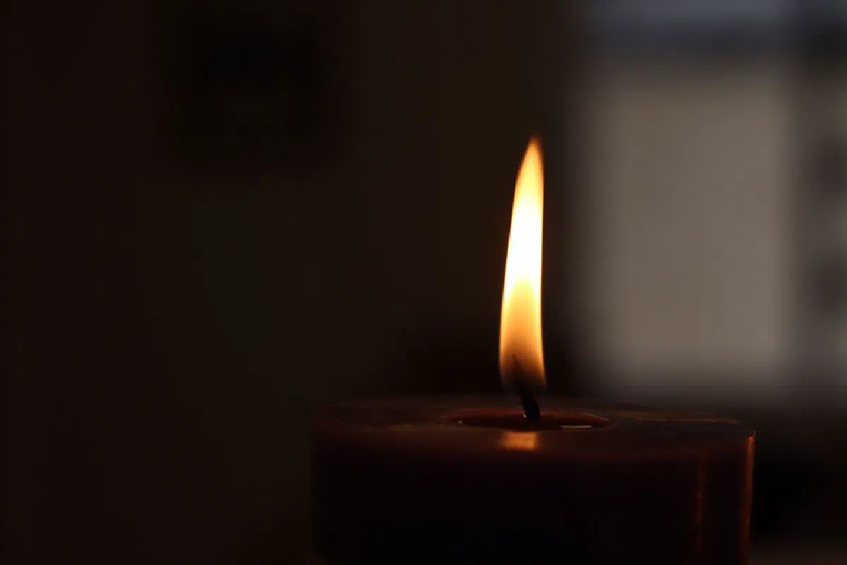 A warm candle flame flickers in the darkness, creating a calming atmosphere.