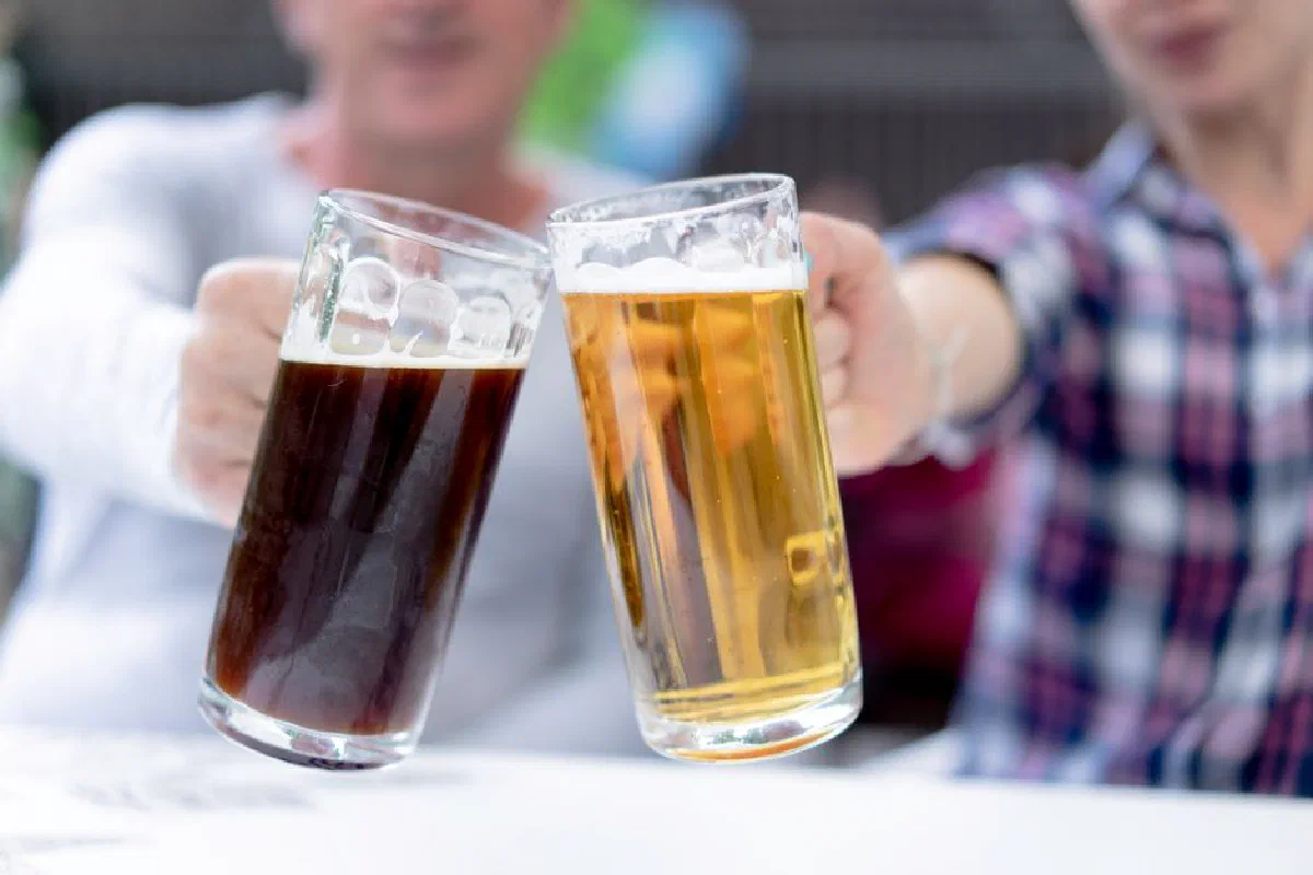 Two men toast with light and dark beer steins at Oktoberfest.