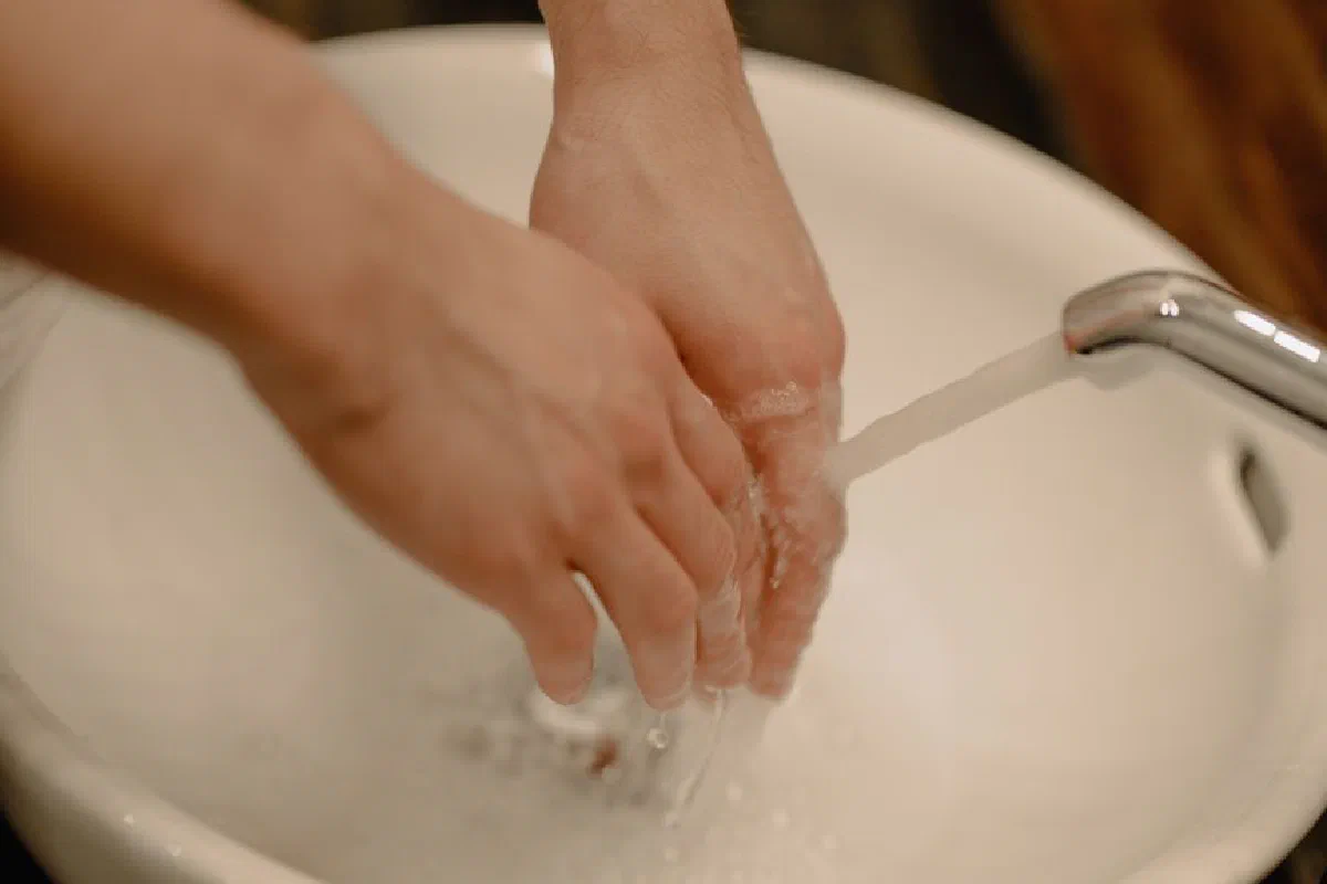 Hands being washed under a running faucet promoting hygiene and health.