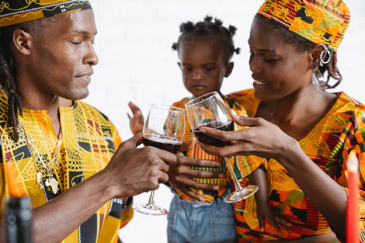 A joyful family toasting with wine, wearing traditional-patterned clothing indoors.