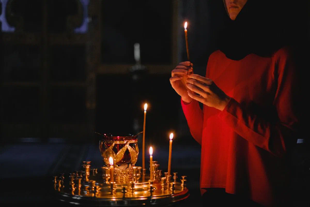 A woman holds a candle in a dimly lit church, highlighting a moment of contemplation and spirituality.