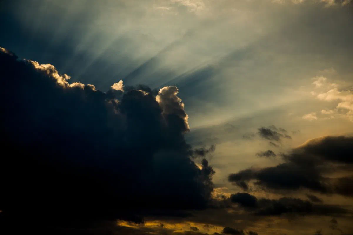 Dark clouds with dramatic sunbeams and a golden twilight sky, creating a sense of hope.
