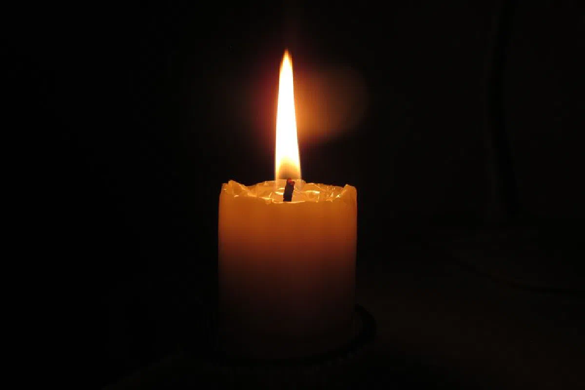 A single candle emits a warm glow in a dark environment, highlighting tranquility.