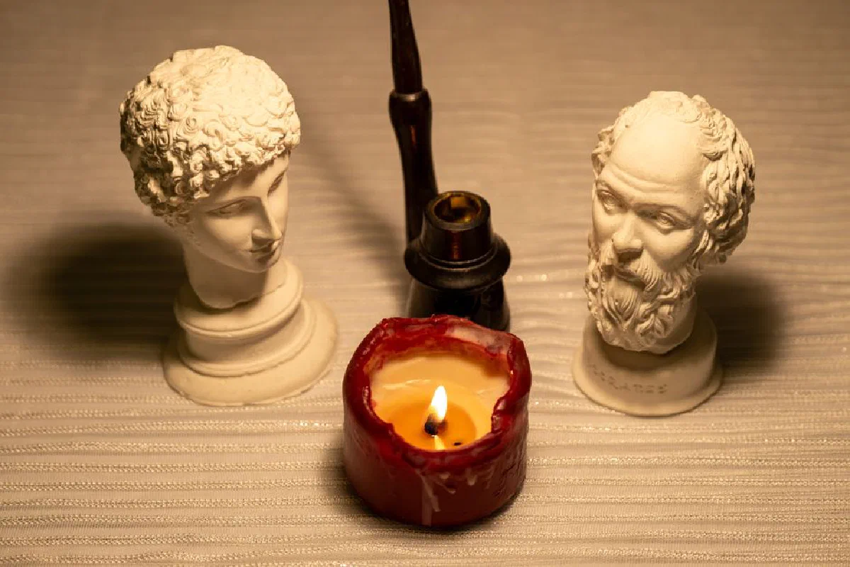 Artistic arrangement of classical busts and candle, creating a serene, elegant setting.