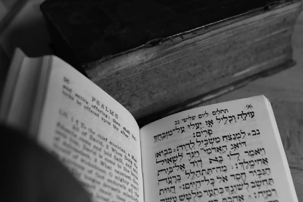 A close-up of an open Psalms book showing Hebrew and English text, creates a reflective mood.