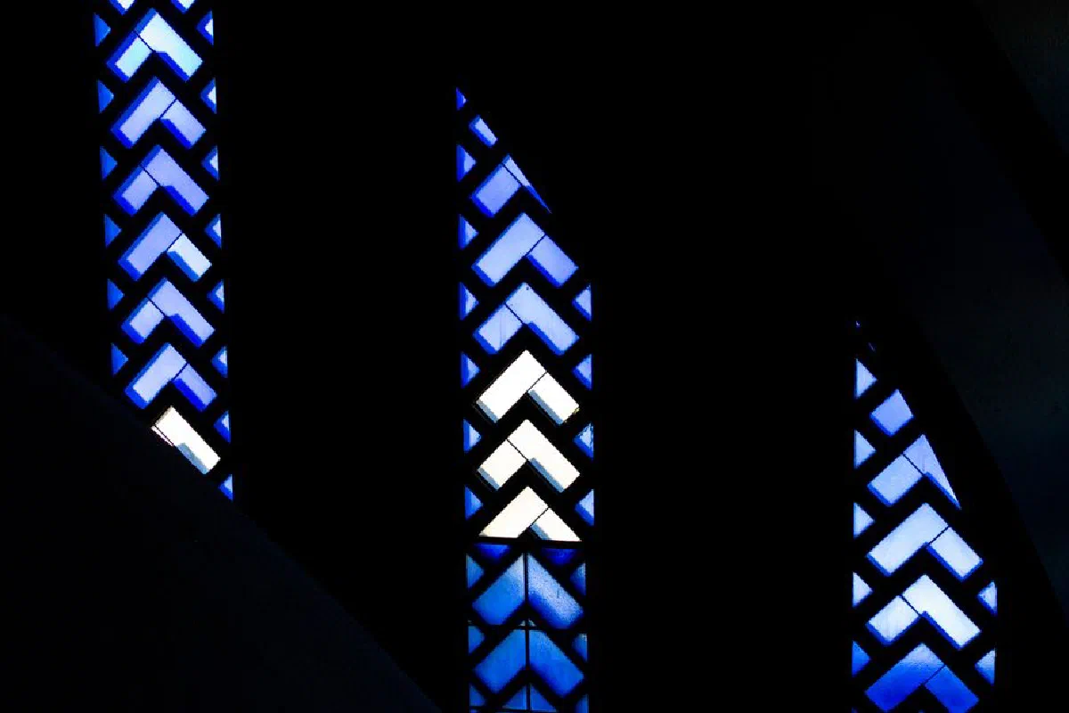 Dark abstract design featuring blue stained glass patterns with geometric shapes.