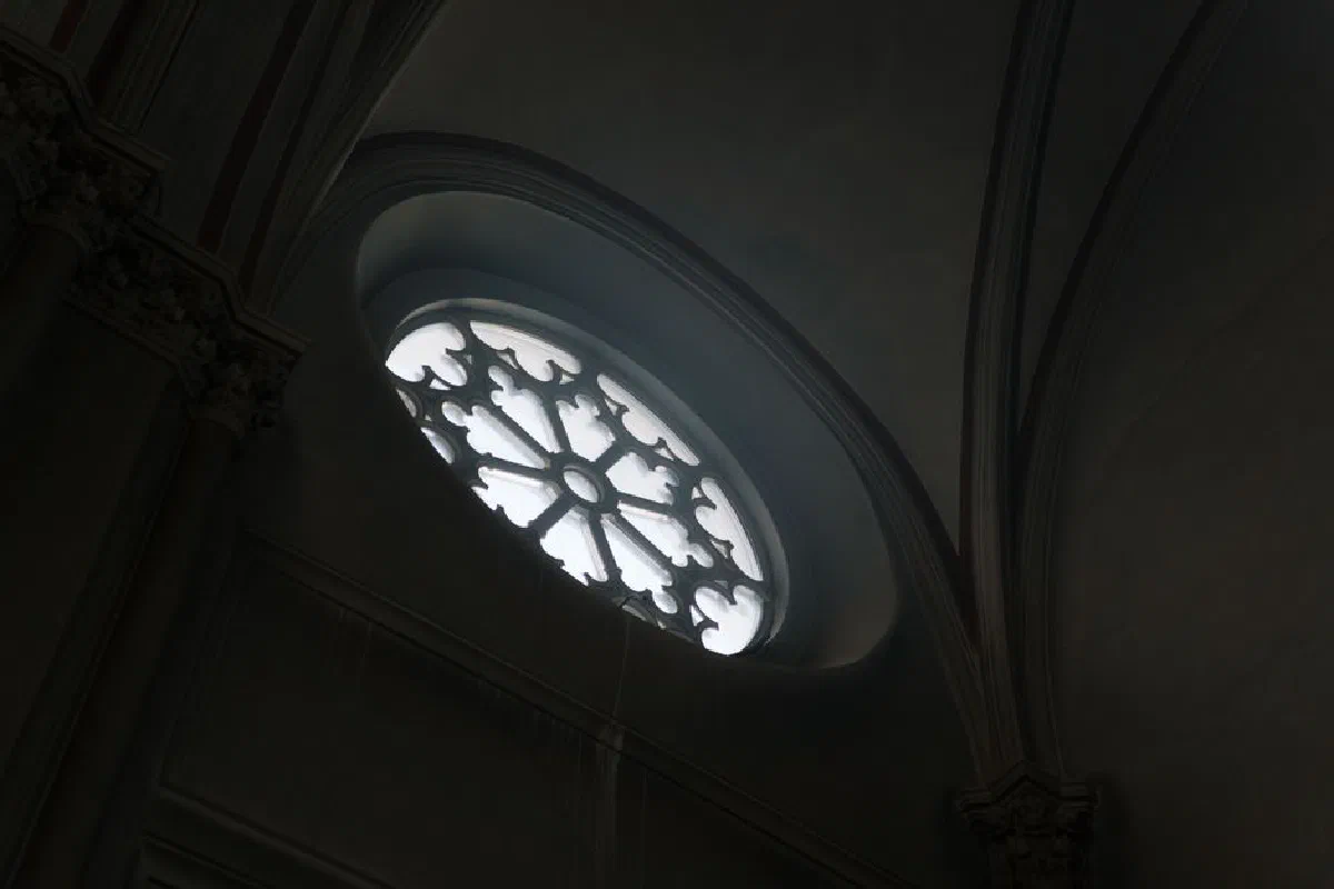 Low-angle view of a Gothic cathedral window showcasing intricate design and natural light.
