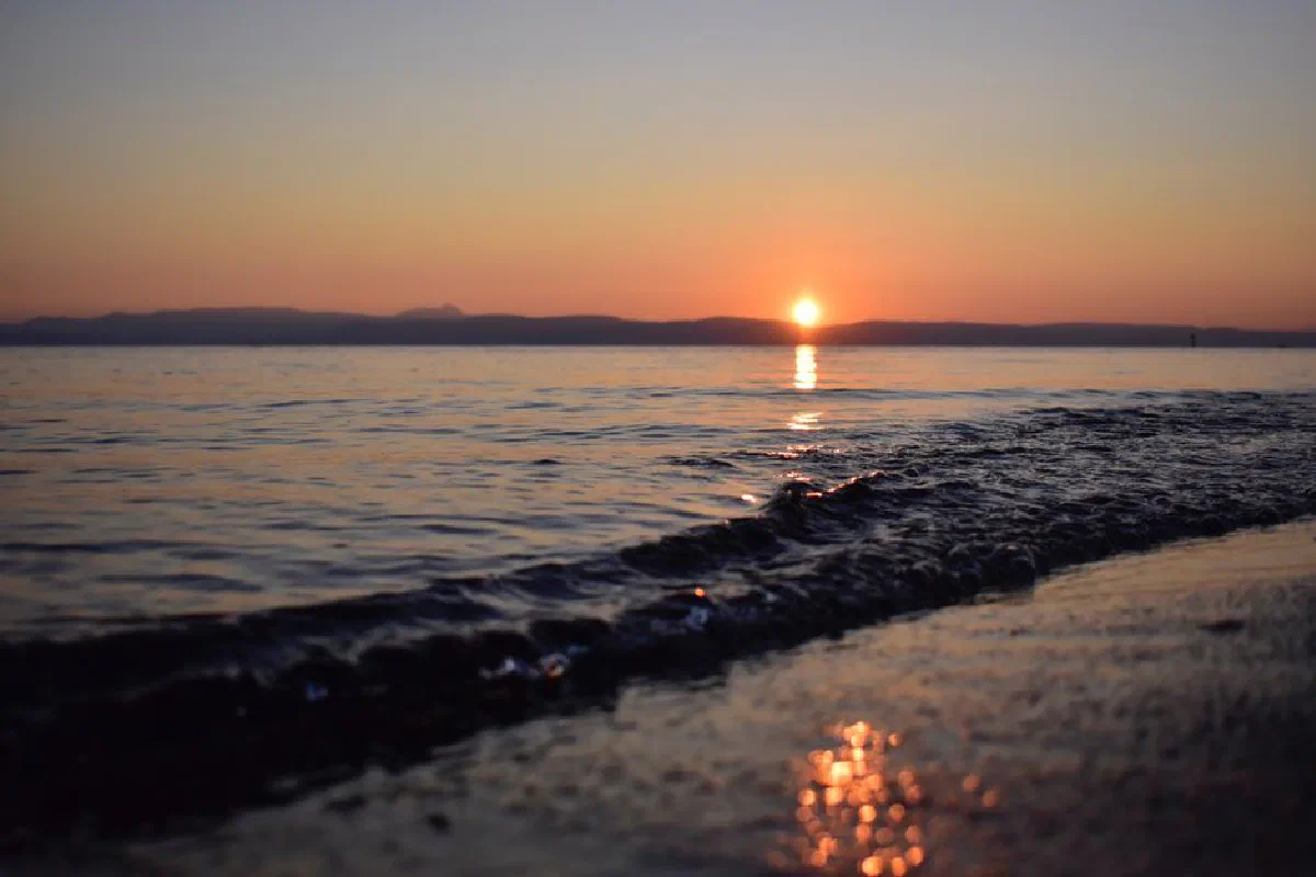 A tranquil beach sunset with gentle waves lapping the shore, creating a peaceful and calming scene.