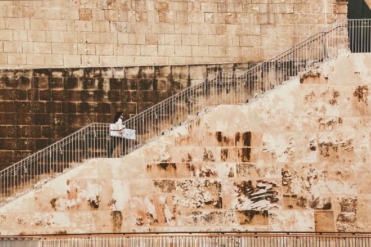 A solitary figure walks up historic stone stairs in Valletta, Malta, showcasing local architecture.