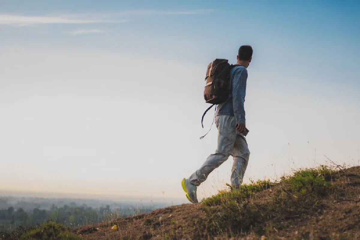 A lone backpacker climbing a hill during sunset, capturing adventure and tranquility in nature.