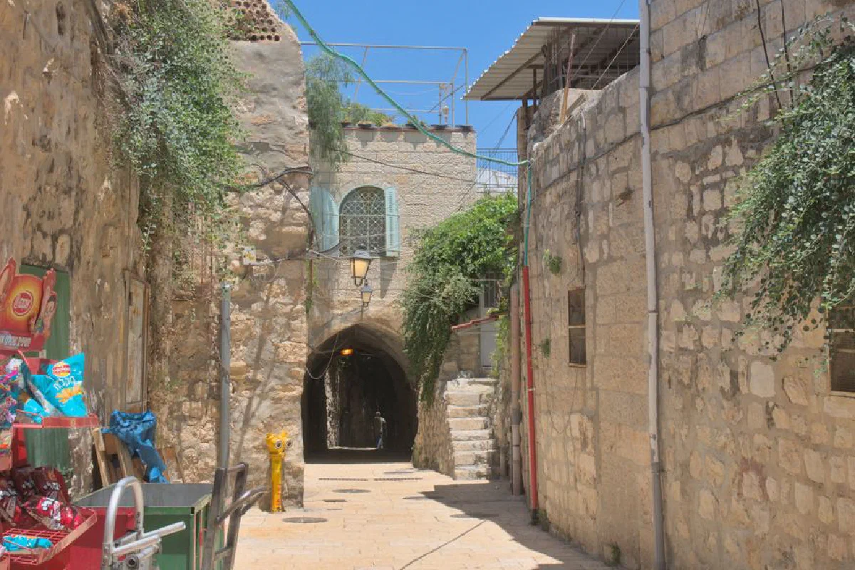 Charming narrow alleyway with cobbled streets in Jerusalem's historic old town, showcasing ancient architecture.