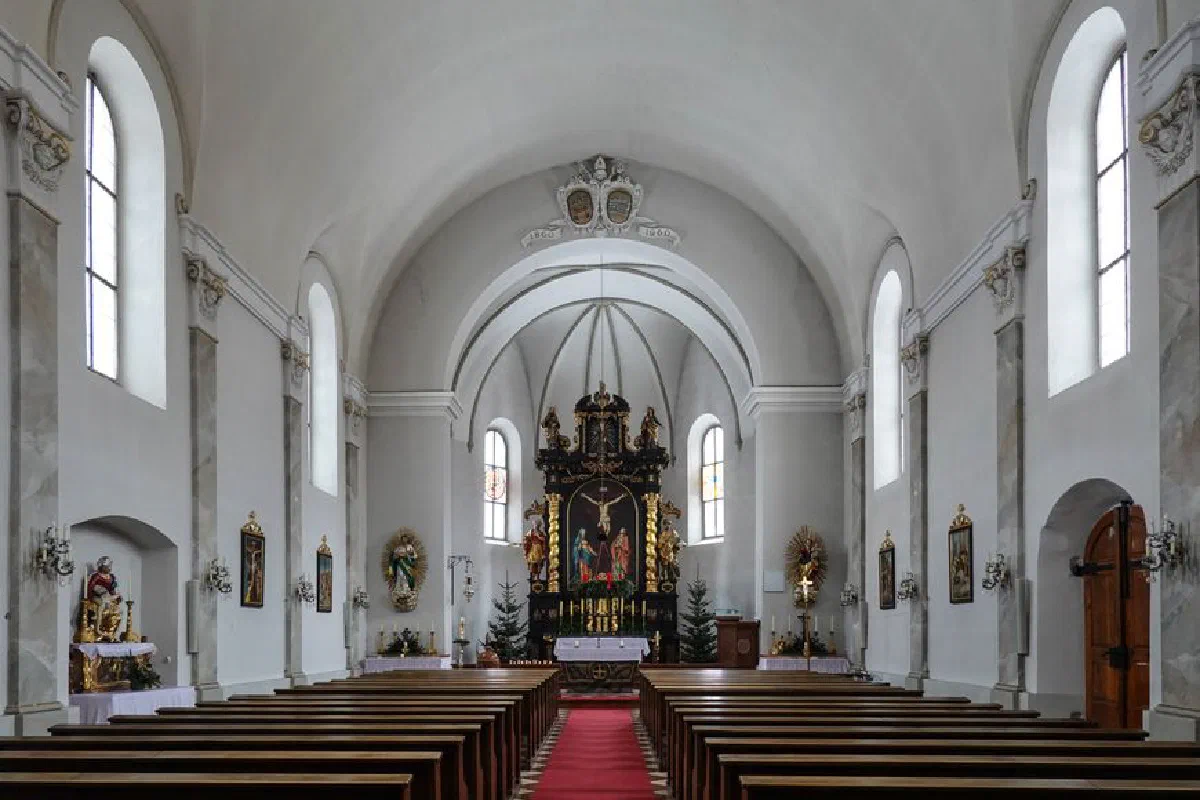 Empty church interior showcasing the altar and pews with natural light streaming through arched windows.