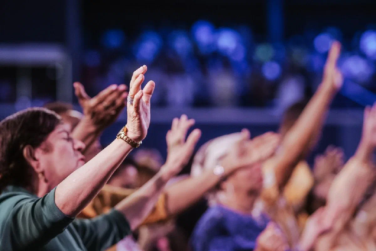A group of people raising hands in unified prayer during a spiritual gathering.