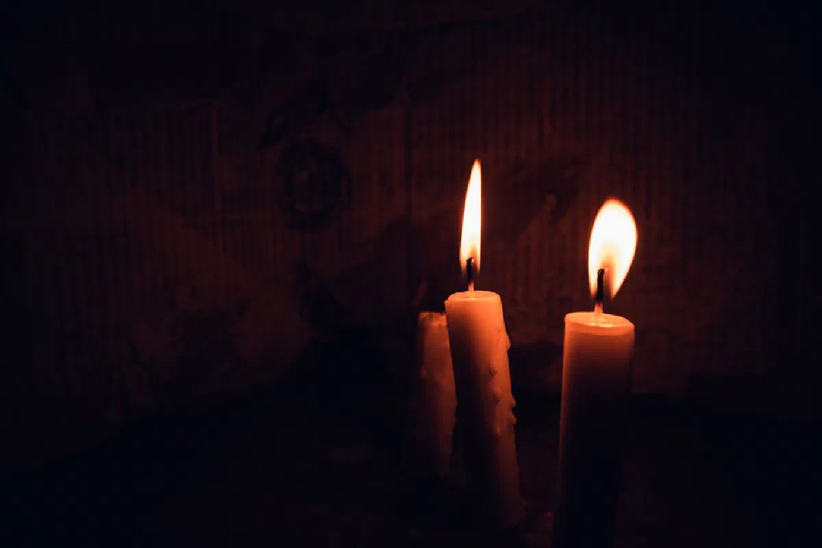 Three lit candles casting warm glow in dark, creating a tranquil and moody ambiance.