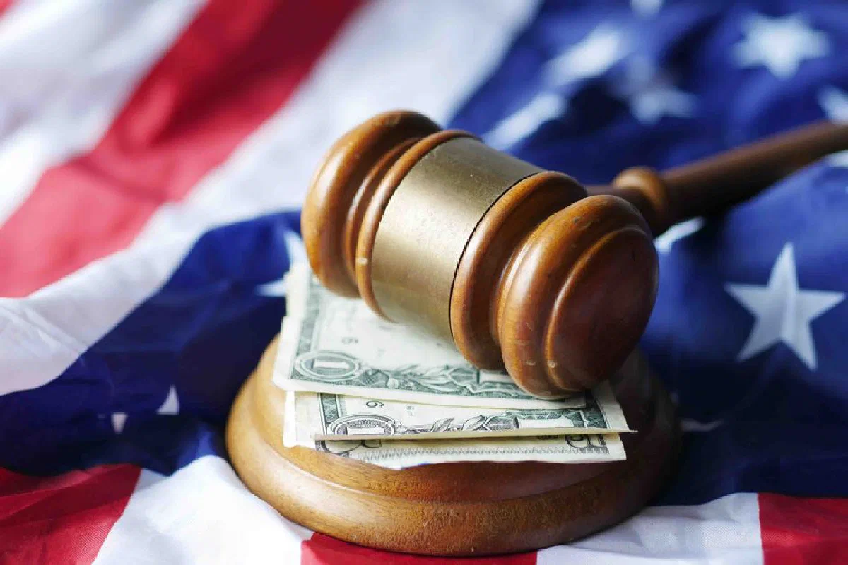 A gavel resting on dollar bills atop the American flag, symbolizing justice and finance.