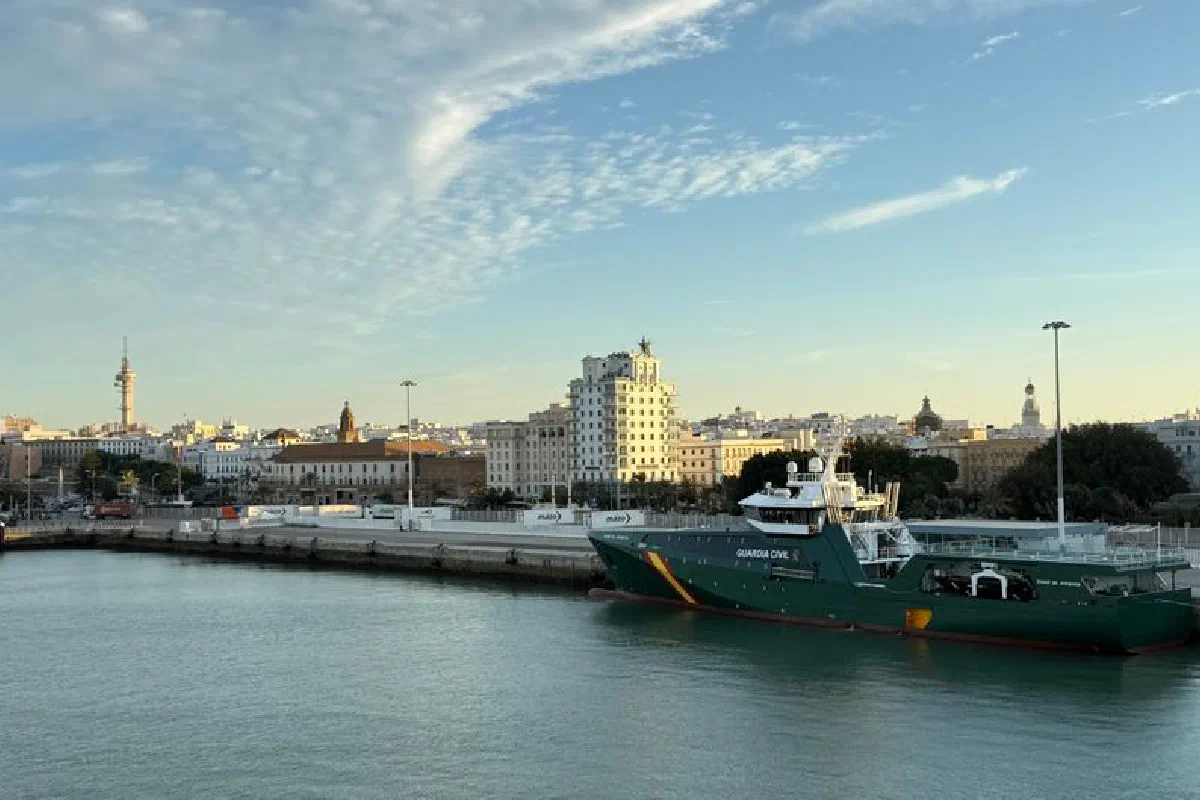 A breathtaking view of Cádiz harbor at day with a Guardia Civil ship and coastal buildings.