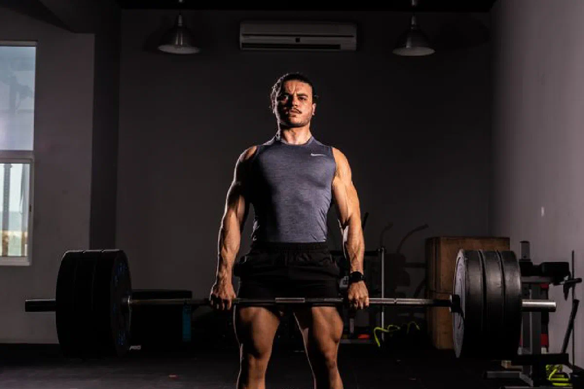 A strong adult man lifting a large barbell indoors, showcasing strength and fitness.
