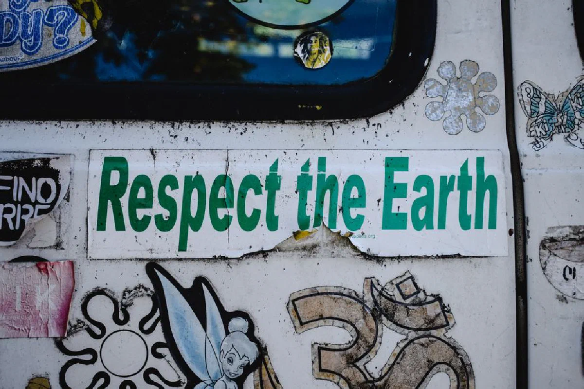 A 'Respect the Earth' sticker surrounded by various designs on a van door in Toronto.