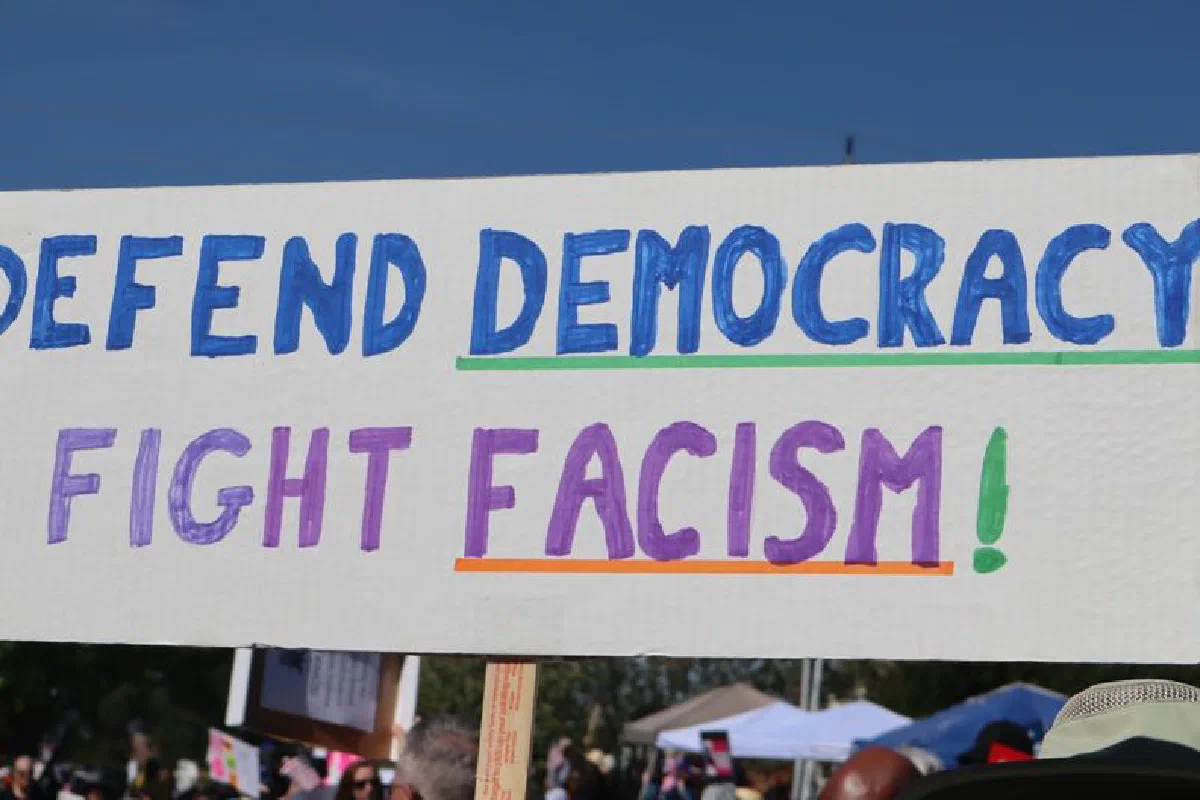 Protest sign reading 'Defend Democracy, Fight Fascism' at an outdoor rally in Elk Grove, CA.