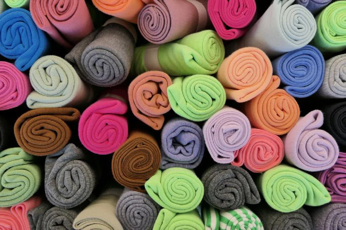Vibrant rolls of fabric arranged neatly, showcasing a rainbow of colors.