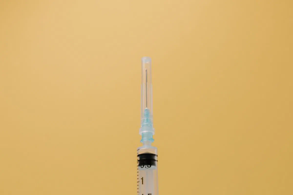 A close-up view of a syringe against a plain yellow backdrop, symbolizing healthcare.