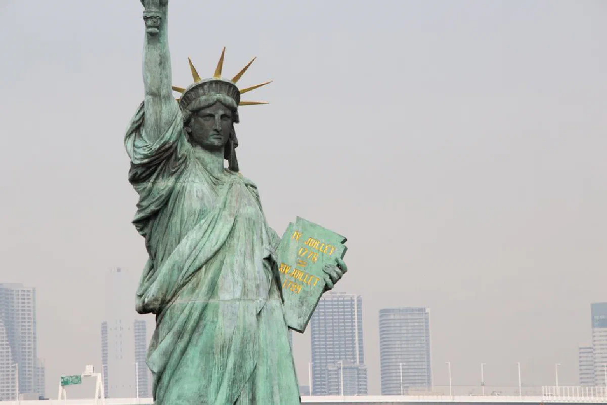 Close-up of the Statue of Liberty replica in Odaiba, Tokyo with skyscrapers in the background.