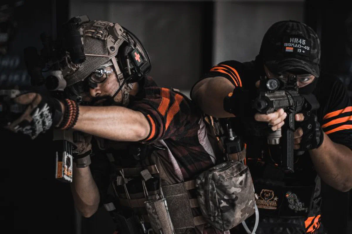 Two armed men in tactical gear engaging in realistic indoor combat training.