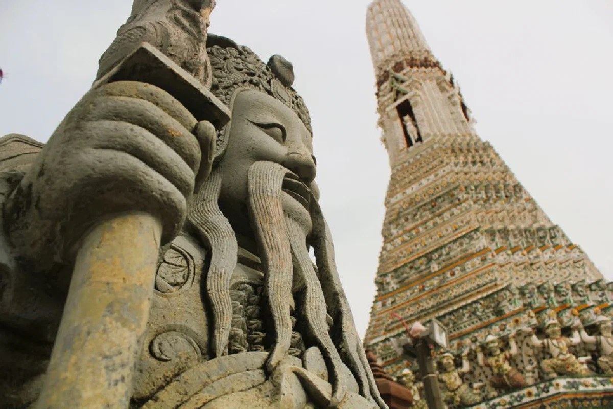 Dramatic close-up of a stone guardian statue at Wat Arun temple in Bangkok, Thailand.