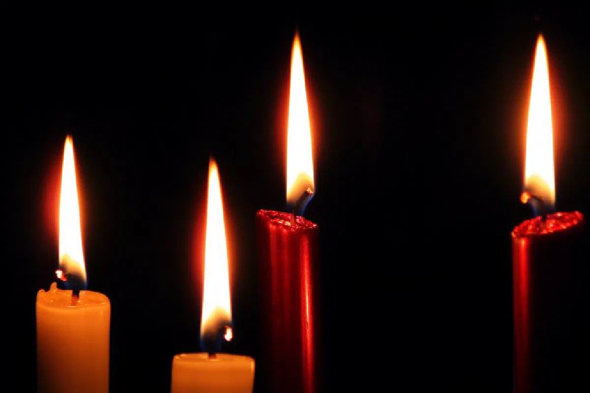 Four colorful taper candles burning brightly against a dark background, creating a warm ambiance.