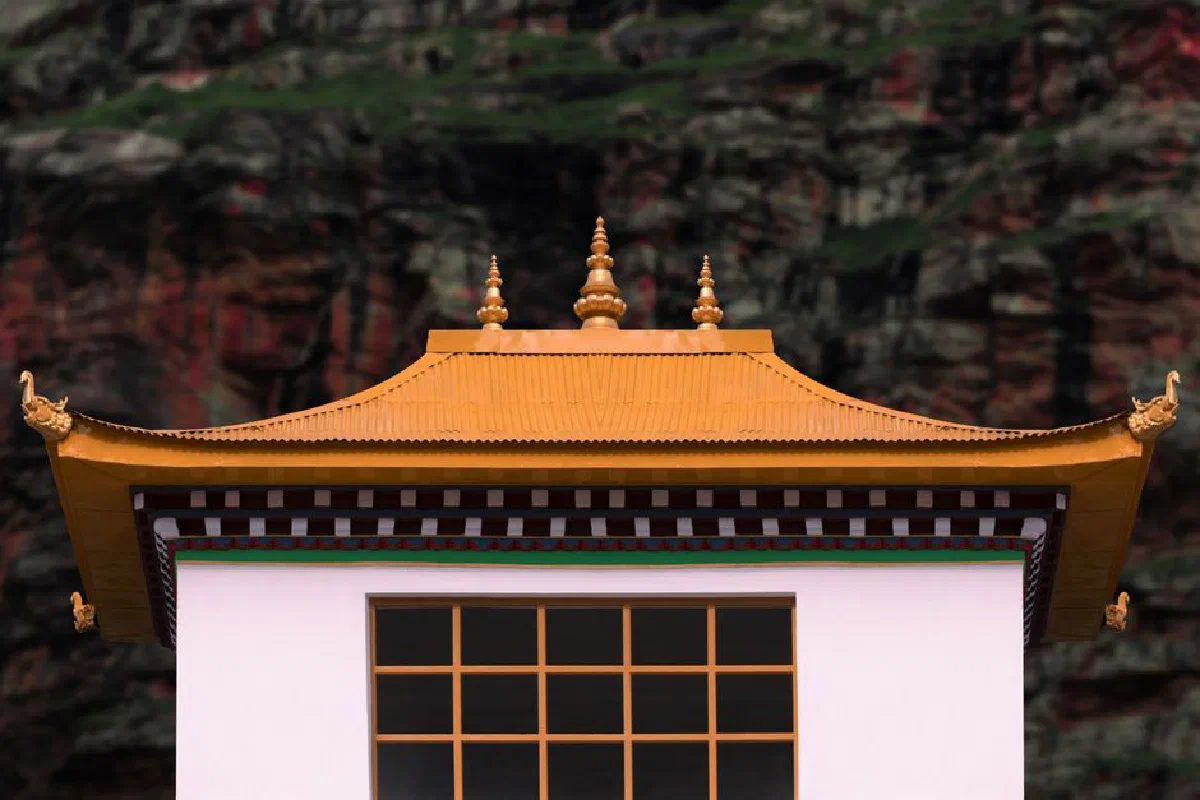 Close-up of a Buddhist temple roof with intricate golden details against a rocky background.