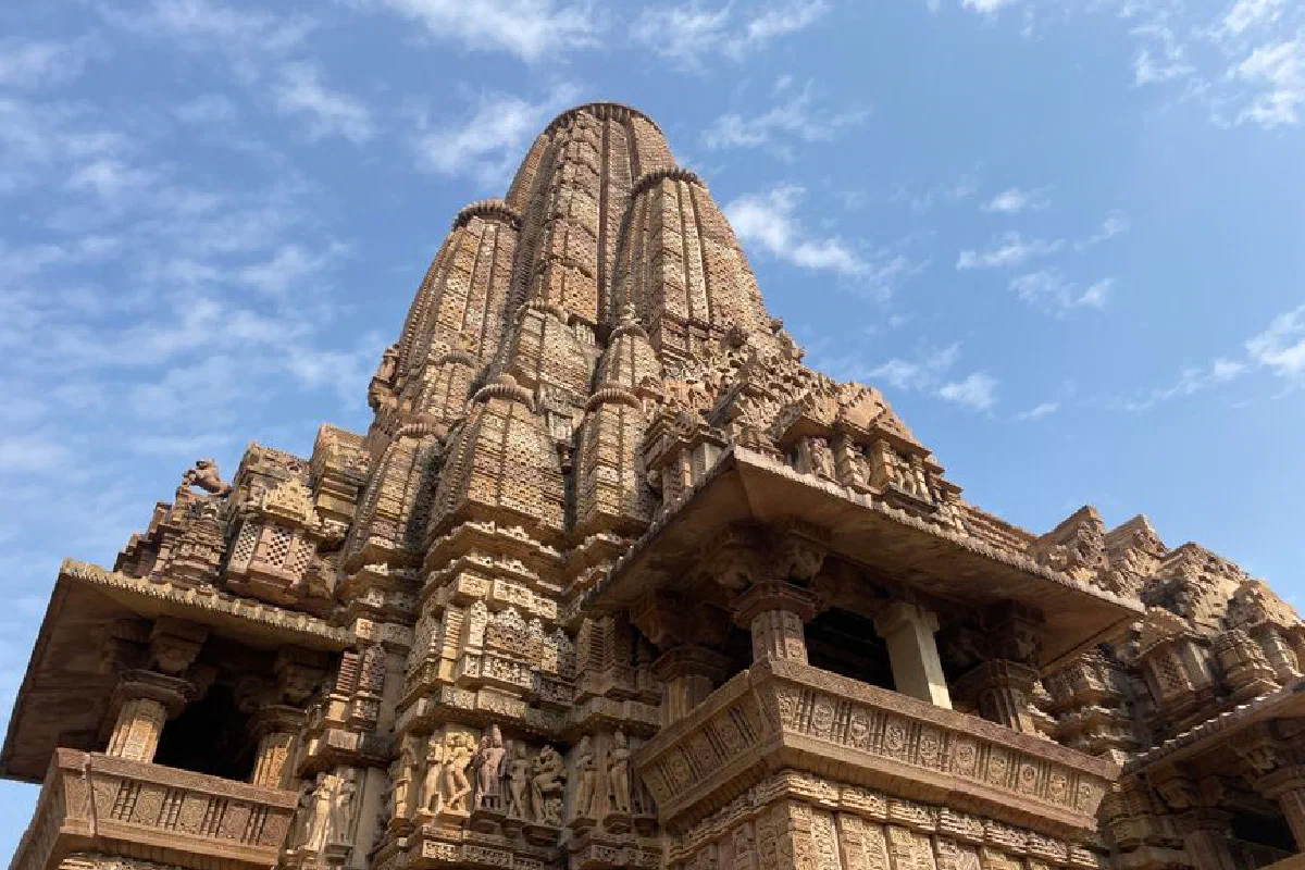 Intricate stone carvings adorn the ancient Khajuraho temple against a clear blue sky.