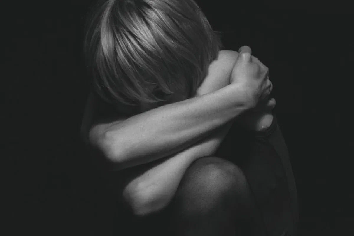 A dramatic black and white portrait capturing deep emotion and solitude in a studio setting.