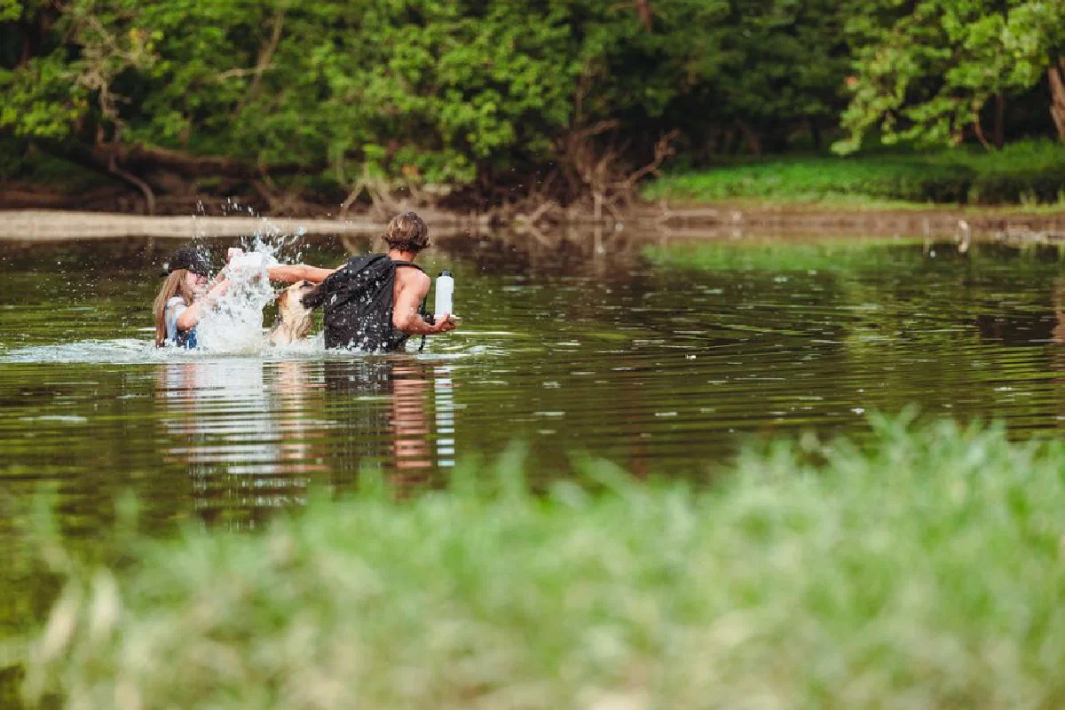 A joyful outdoor adventure with a couple and their dog playing in the lake, embracing nature.