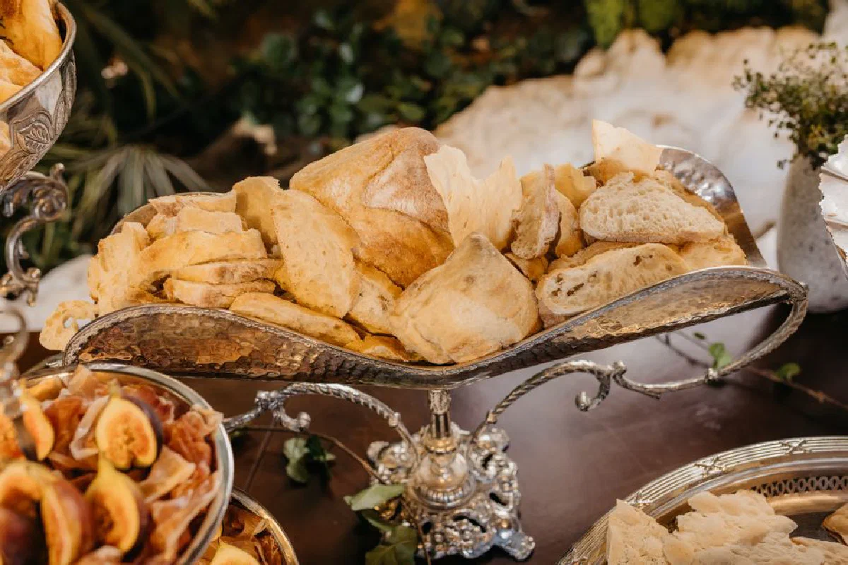 Elegant display of assorted bread in a vintage silver tray at a rustic table setting.
