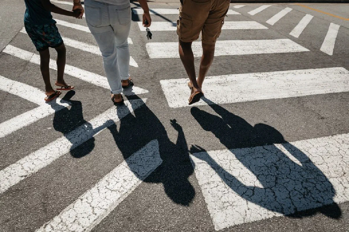A family walking across a zebra crossing, representing safety and care.