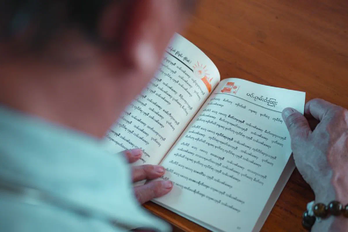 An adult reading a book with religious texts in Bangkok, Thailand.