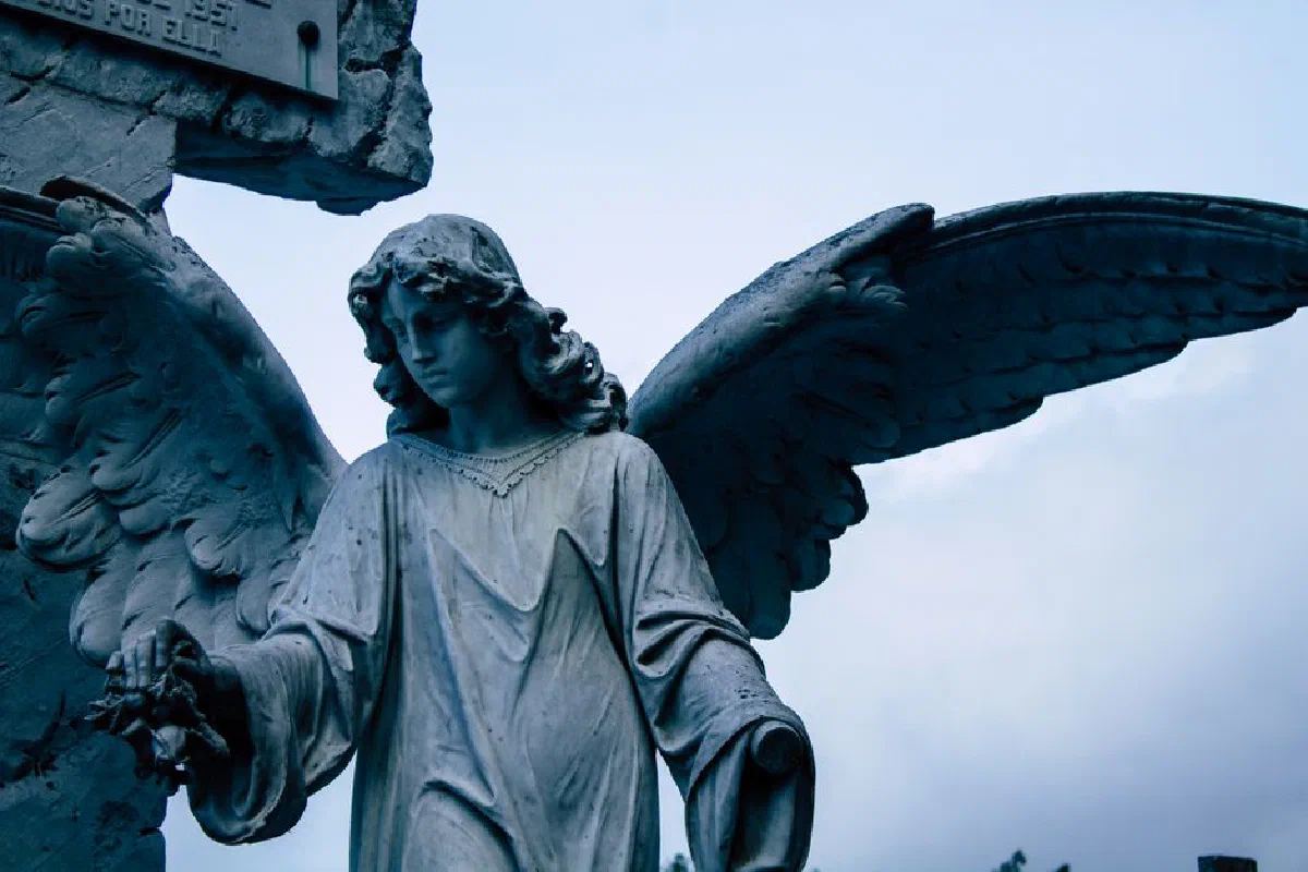Close-up of a marble angel statue with majestic wings against the sky.