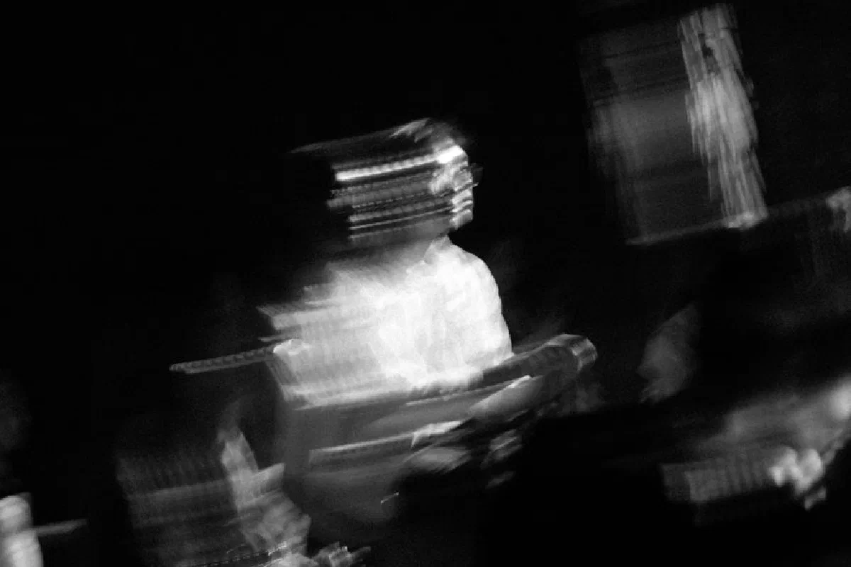 Blurry black and white artistic shot of musician in motion, evoking movement.