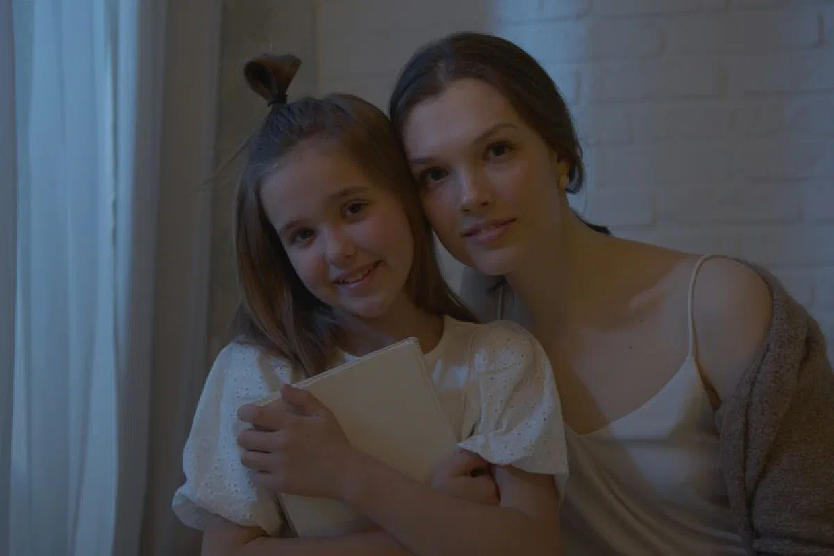 A close embrace between a mother and daughter indoors, reflecting love and warmth.