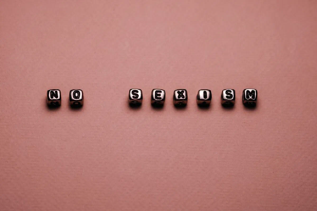 Cubes spelling 'No Sexism' on a brown background symbolizing gender equality.