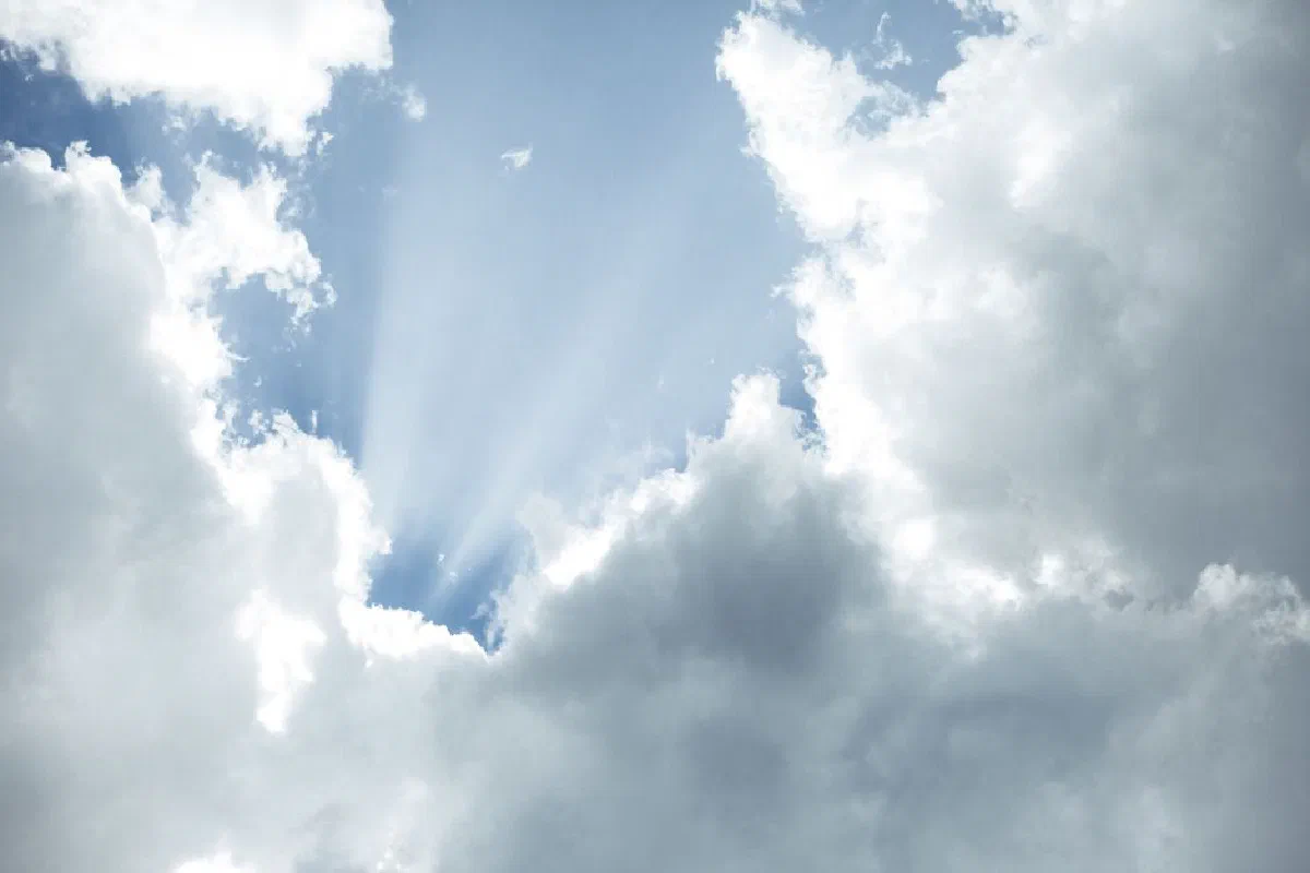Sunlight streaming through dramatic clouds against a vibrant blue sky.