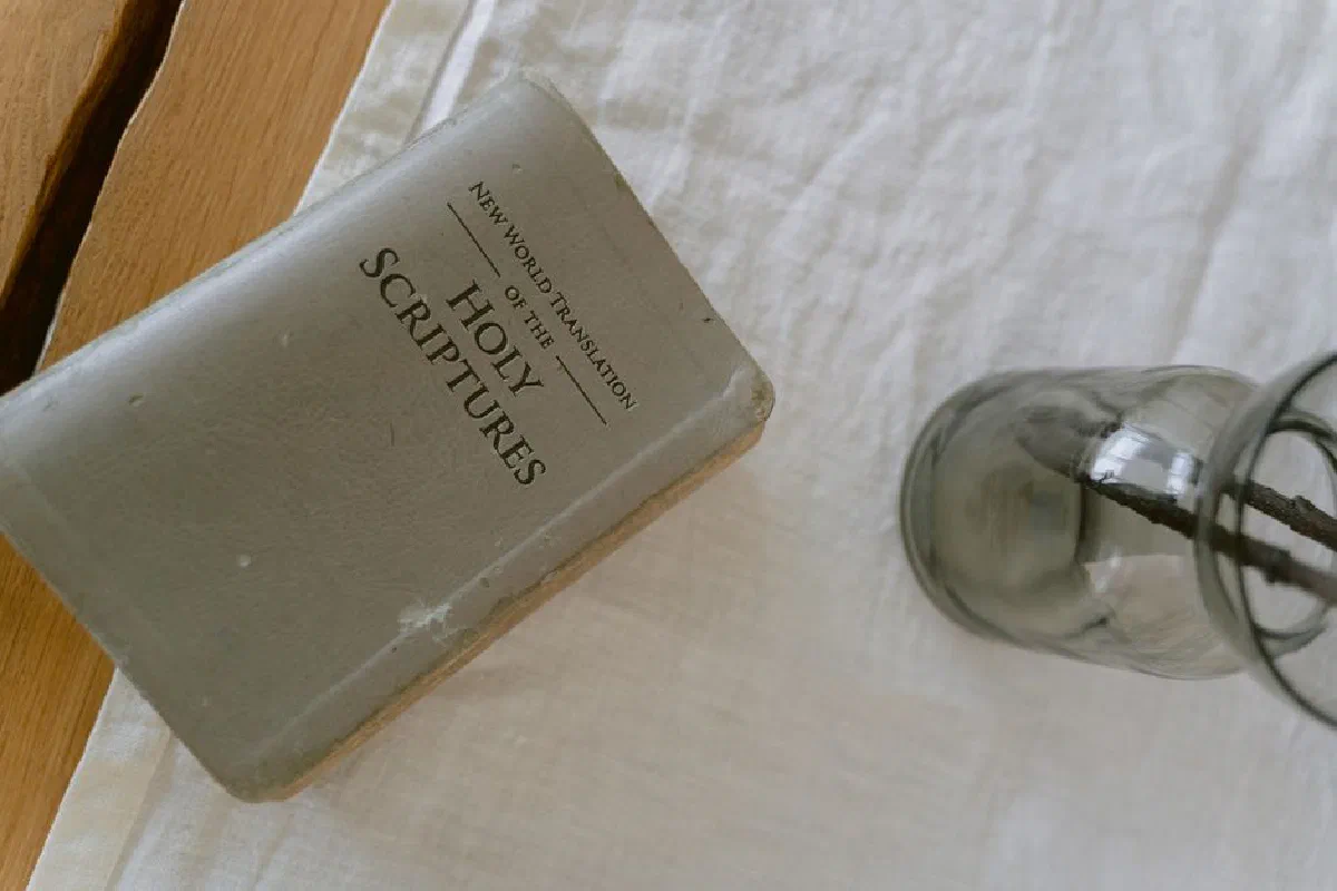 A vintage Holy Bible on linen cloth, accompanied by a glass vase, shot from above.