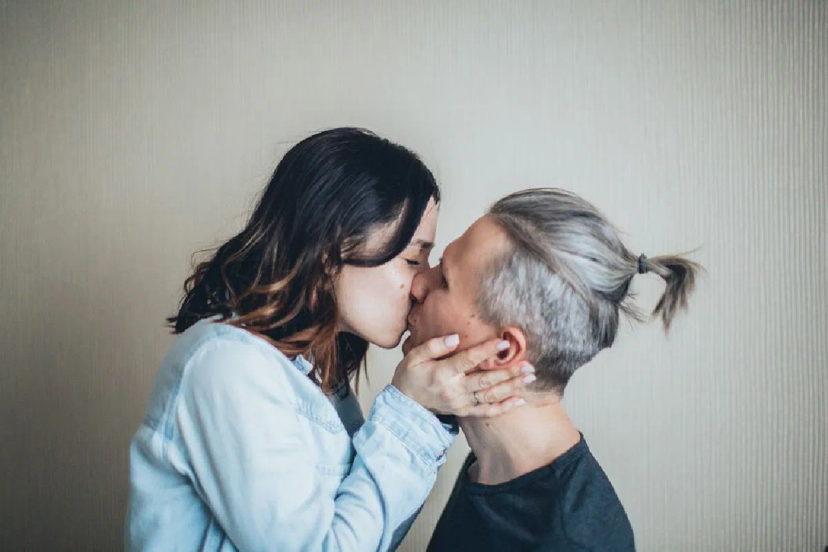 A couple sharing a tender kiss indoors, capturing a moment of love and affection.