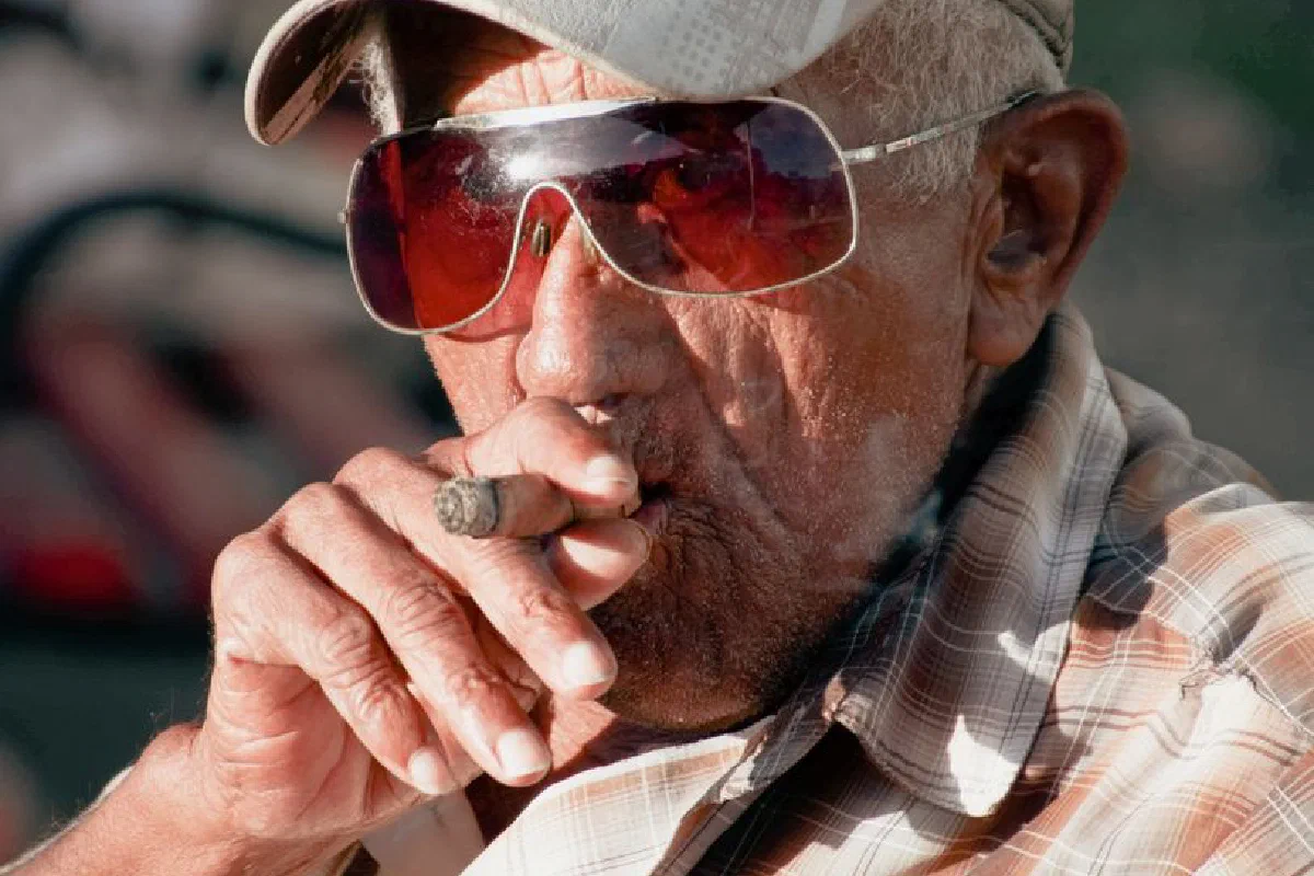 Close-up of a senior man smoking a cigar, showcasing leisure and lifestyle.