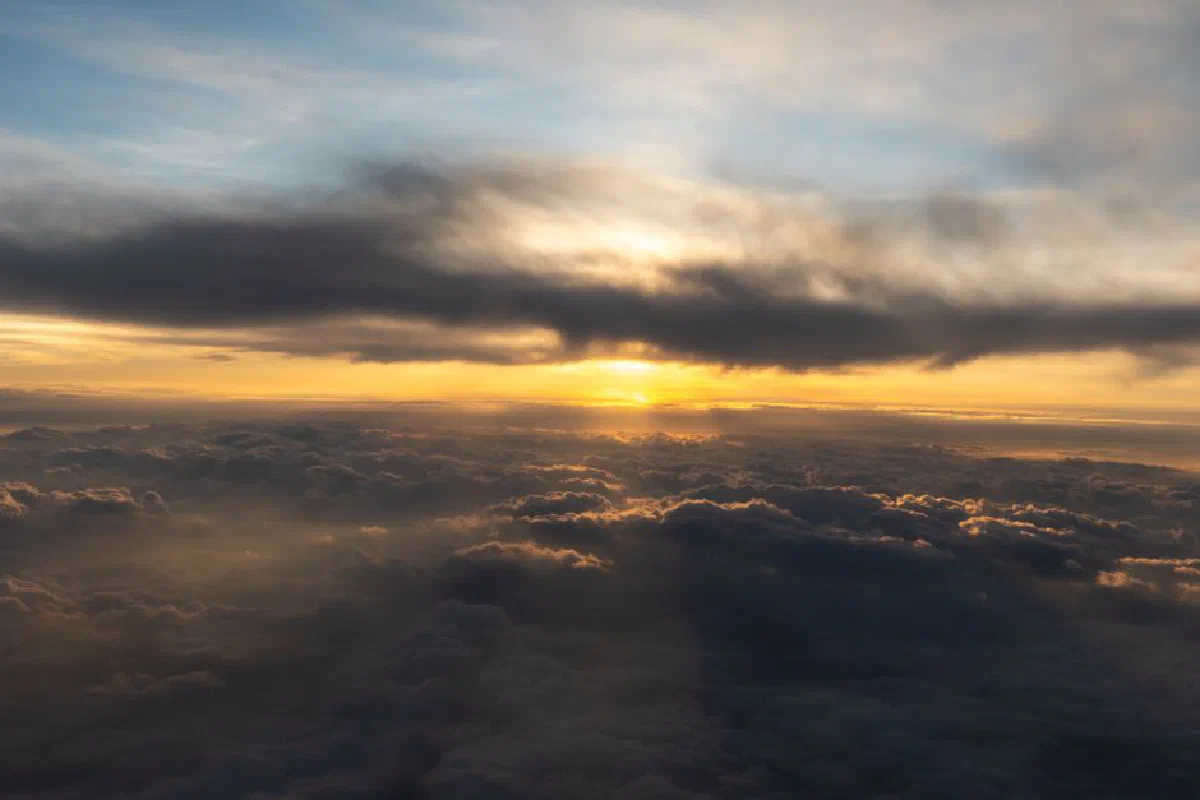 Breathtaking aerial view of sun rising above the clouds, casting warm golden light.