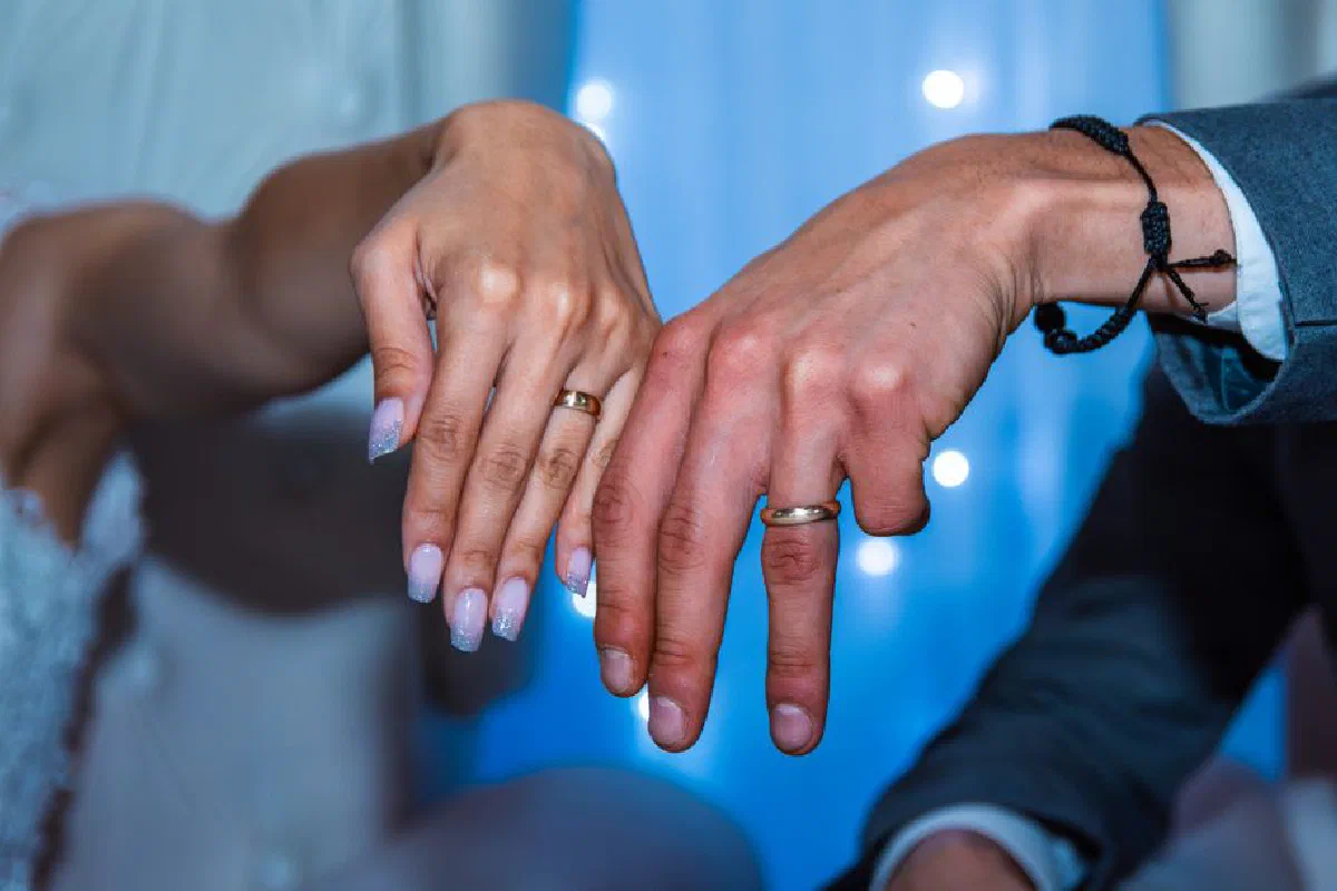 A couple showcasing their wedding rings at a ceremony, symbolizing love and commitment.